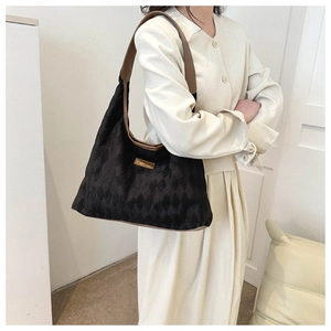 Close-up of quilted black tote with brown leather strap and gold 'Fashion' metal plate