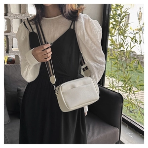Close-up of cream crossbody bag featuring lychee texture leather and striped fabric strap