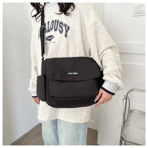 Dettaglio di una grande borsa a tracolla in nylon nero con patta e tasca laterale