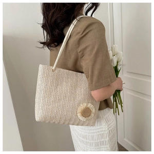 Detail of hand-woven straw tote bag with sunflower accent and white rope strap