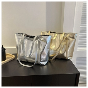 Close-up of metallic silver and gold tote bags with glossy finish on a dark surface
