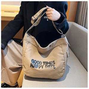 Detail view of khaki canvas tote bag featuring adjustable strap and graphic typography