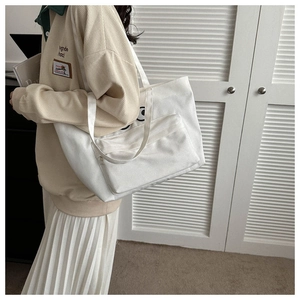 Detailed view of white canvas tote bag with cartoon eye pattern and front zipper pocket