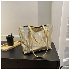 Close-up of a large metallic gold tote bag with a minimalist design and long handles