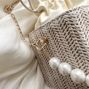 Woven straw bucket bag with pearl chain strap and drawstring closure for women