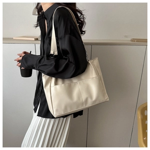 Detail view of large cream leather tote bag with functional double front pockets