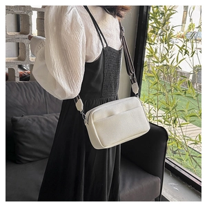 Détail du sac bandoulière blanc en cuir grainé avec une large sangle rayée