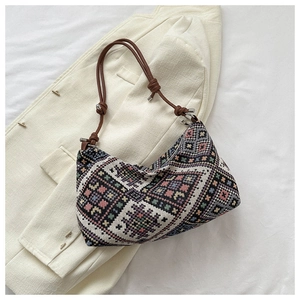 Detail of bohemian geometric jacquard fabric and brown leather strap on a shoulder bag
