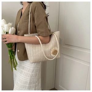 Detail of woven beige tote bag featuring 3D floral accents and dual rope shoulder straps