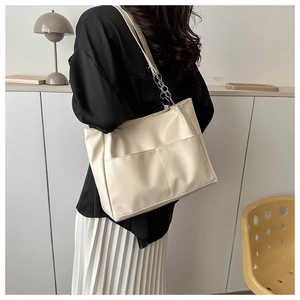 Detail of soft cream tote bag featuring front pockets and silver chain shoulder strap