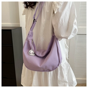 Detail of purple crescent shoulder bag with cute cartoon dog pendant and wide strap