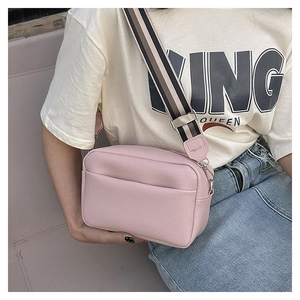 Detail view of pink lychee leather camera bag with striped wide textile strap