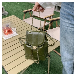 Close-up of deep green retro oil wax leather backpack with gold chain and twist lock