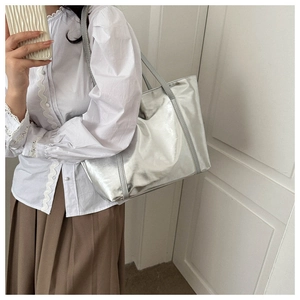 Detailed side view of large silver metallic tote bag featuring sleek slim shoulder straps