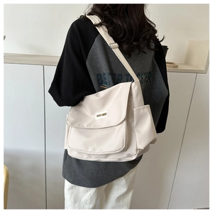 Detail of cream canvas messenger bag showing a side view on a model with wide strap