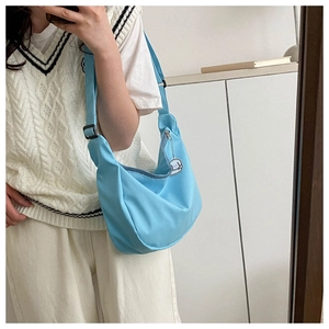 Detail of light blue crescent hobo bag with a white cartoon charm and adjustable strap