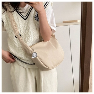 Mirror selfie showing a cream crescent crossbody bag with a cute white puppy pendant