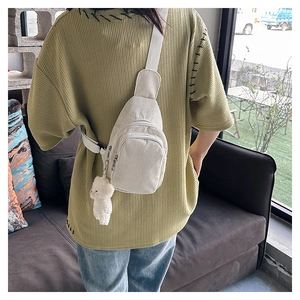 Corduroy waist bag in cream white worn across the back featuring a plush bear charm