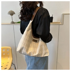 Close-up of beige quilted tote bag with brown leather straps and Fashion label on model