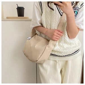 Close-up of beige corduroy crossbody bag with soft texture and cartoon dog pendant