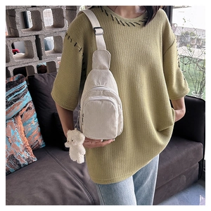 Detailed shot of white corduroy crossbody bag with cute plush bear charm on strap