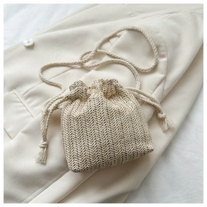 Detailed close-up of woven straw bucket bag texture and drawstring strap on white fabric