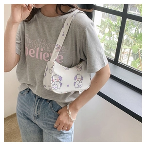 Detailed view of white cartoon printed shoulder bag with purple dog motif on female model