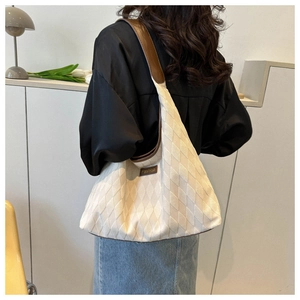 Close-up of beige quilted tote bag with brown leather straps and fashion label detail