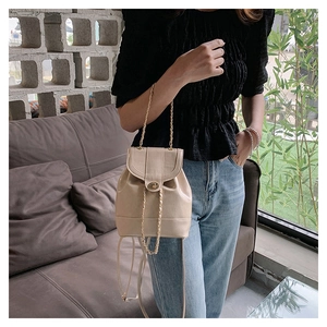 Close-up of a beige mini bucket bag with gold chain straps and a twist-lock metal clasp