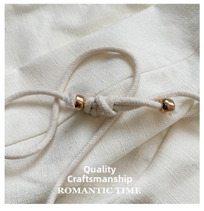 Detail of woven straw bucket bag showing cream fabric texture and gold metal beads
