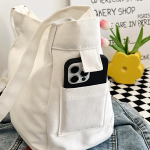 Minimalist white canvas shoulder bag with functional side pocket for smartphone storage
