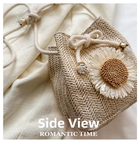 Detailed side view of straw bucket bag featuring woven texture and white flower applique