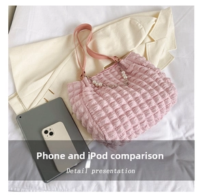 Detail of pink quilted tote bag with pearl chain shown next to a smartphone and tablet