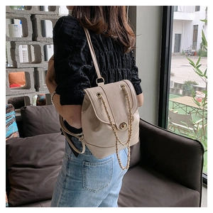 Close-up of beige textured leather backpack with gold chain straps and metal twist lock