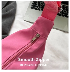 Close-up of the smooth metal zipper and nylon strap on a pink crossbody bag