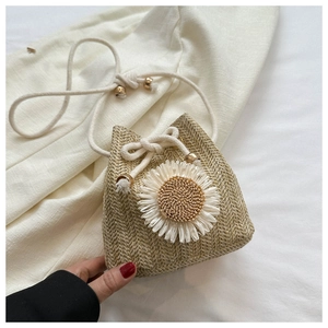 Detailed texture of straw bucket bag featuring a large white 3D flower and rope closure