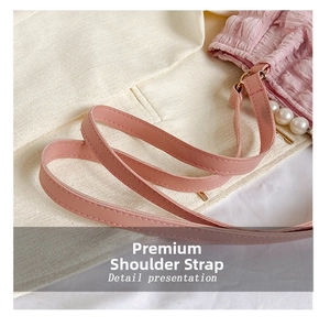 Detail of pink PU leather shoulder strap with elegant pearl pendant on a quilted tote