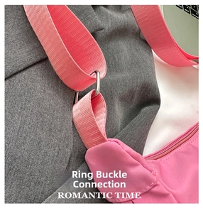 Detail of pink shoulder bag showing wide fabric strap and silver metal ring connector