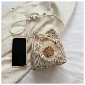 Close-up of hand-woven straw bucket bag with sunflower detail and drawstring strap