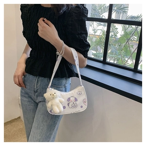 Close-up of white underarm bag with cute cartoon dog pattern and plush bear charm
