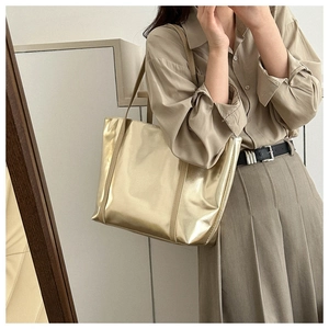 Close-up of golden metallic tote bag styled with beige outfit in modern minimalist setting