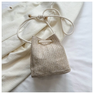 Detail of straw woven bucket bag with herringbone texture and drawstring closure