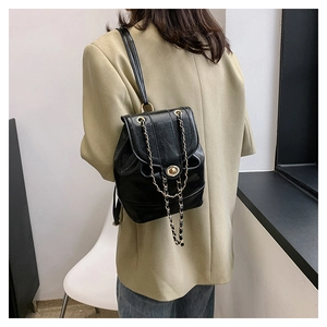 Detail of black faux leather mini backpack featuring gold chain straps and turn-lock