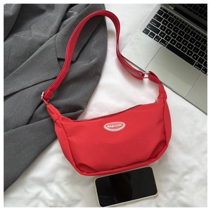 Detailed view of a red nylon crescent crossbody bag with white FASHION logo label