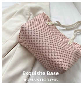 Close-up of pale pink tote bag with textured faux leather and gold protective base studs