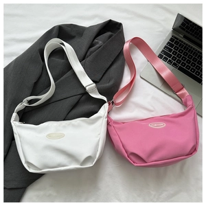Detail view of crescent nylon crossbody bags in pink and white with adjustable straps