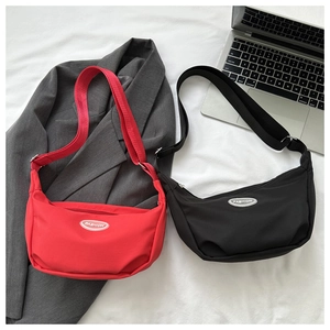 Close-up of red and black nylon crescent moon bags with adjustable wide shoulder straps