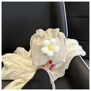 Close-up of beige woven bucket bag with 3D white knitted flower and drawstring details