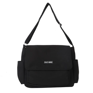 Borsa a tracolla in tela nera con tracolla regolabile e toppa logo su sfondo bianco