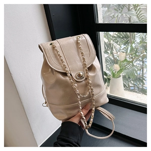 Detail of metal twist lock and gold chain strap on cream oil wax leather backpack